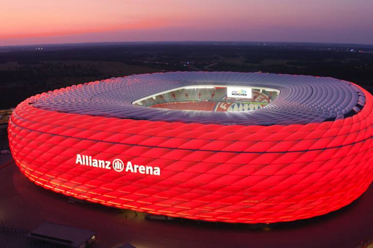 Allianz Arena illuminated in red at night.